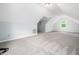 A spacious attic area with carpet, light blue walls, and a window providing natural light at 12823 Summerwind Trl, Rougemont, NC 27572