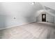 View of an open attic space with carpet, light blue walls, and a dark wooden door at 12823 Summerwind Trl, Rougemont, NC 27572