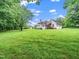 Lush green backyard showcasing the expansive lawn, mature trees, and the home's exterior at 12823 Summerwind Trl, Rougemont, NC 27572