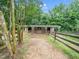 A barn with spacious stalls and a rustic fence, offers a secure and comfortable environment for animals at 12823 Summerwind Trl, Rougemont, NC 27572