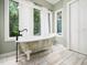 Bright bathroom features a clawfoot tub with black fixtures and three large windows providing natural light at 12823 Summerwind Trl, Rougemont, NC 27572