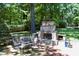 Custom stone outdoor fireplace with built-in seating and lush greenery at 1300 Keynes Ct, Raleigh, NC 27615