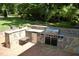 Outdoor kitchen with stainless steel grill, mini fridge, and stone countertops at 1300 Keynes Ct, Raleigh, NC 27615