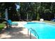 Sparkling in-ground pool with poolside seating, umbrellas, and a lush green surrounding landscape at 1300 Keynes Ct, Raleigh, NC 27615