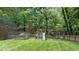 Fenced backyard featuring a playset, ample lawn space, and mature trees, providing a safe and fun environment for children at 1332 Kinsdale Dr, Raleigh, NC 27615
