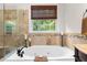 Elegant bathroom featuring a soaking tub and a tiled shower with a glass door at 1332 Kinsdale Dr, Raleigh, NC 27615