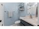 This bathroom features a single vanity, open shelving, tiled shower, and light blue painted walls at 1332 Kinsdale Dr, Raleigh, NC 27615