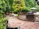Outdoor living space with brick patio, wooden deck, and grill, surrounded by lush landscaping at 1706 Rangecrest Rd, Raleigh, NC 27612