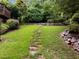 Green lawn and a stepping stone path lead to a rock wall and mature landscaping at 1706 Rangecrest Rd, Raleigh, NC 27612