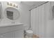 Bright bathroom with white vanity, round mirror, neutral floor tiles and a shower with a white curtain at 1706 Rangecrest Rd, Raleigh, NC 27612