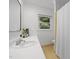 Bright bathroom with a mirror, white countertop sink, and a window with a view of lush green trees at 1706 Rangecrest Rd, Raleigh, NC 27612