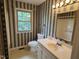 Bathroom with patterned wallpaper, vanity, toilet, and shower showcasing traditional design elements at 1942 Brier Ln, Graham, NC 27253