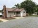 A beige home featuring a new roof, exterior doors, and gravel driveway at 1942 Brier Ln, Graham, NC 27253