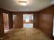 Spacious living room featuring wood paneling, multiple doorways, and carpet flooring for warmth and comfort at 1942 Brier Ln, Graham, NC 27253