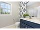 Bathroom featuring a modern vanity, decorative mirror, and stylish wallpaper at 20 Wood Ibis Way, Louisburg, NC 27549