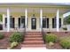 Inviting front porch with black railings, brick steps, and rocking chairs at 20 Wood Ibis Way, Louisburg, NC 27549