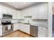 Well-lit kitchen features stainless steel appliances, white cabinetry, granite countertops, and a wood floor at 20 Wood Ibis Way, Louisburg, NC 27549