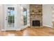 Living room with a stone fireplace, hardwood floors, and large windows with outdoor views at 20 Wood Ibis Way, Louisburg, NC 27549