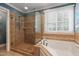 Bathroom featuring a tiled shower with a glass door, a soaking tub, and a window at 200 Cobblepoint Way, Holly Springs, NC 27540