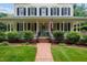 Classic home with a inviting front porch, featuring an American flag and manicured landscaping at 200 Cobblepoint Way, Holly Springs, NC 27540