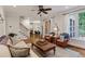 Inviting living room with wood floors, woven chairs, a ceiling fan, and staircase at 200 Cobblepoint Way, Holly Springs, NC 27540