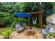 Backyard stone patio area featuring outdoor seating, a hammock, and a vibrant blue umbrella at 200 Cobblepoint Way, Holly Springs, NC 27540