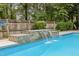In-ground pool features a lovely waterfall feature with stone surround and tiled pool edge, surrounded by a wooden fence at 2001 Dobson Ct, Raleigh, NC 27612
