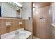 A full bathroom with seashell wallpaper, vanity, and shower featuring brown tiling at 2016 Tryon Rd, Raleigh, NC 27603
