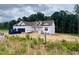 New construction home featuring Tyvek wrap, dormers, attached garage, and partially cleared lot ready for finishing touches at 204 Seahawk Way, Zebulon, NC 27597