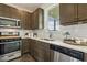 Well-lit kitchen with stainless steel appliances, white backsplash, dark cabinets, and granite countertops at 225 Rosewood Ln, Youngsville, NC 27596