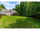 Lush green backyard featuring a white house with a screened-in porch and deck, bordered by mature trees at 228 Birch Creek Dr, Fuquay Varina, NC 27526