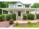 Charming covered porch featuring stone accents and meticulously manicured landscaping at 228 Birch Creek Dr, Fuquay Varina, NC 27526
