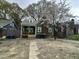 Charming green home featuring a cozy front porch, flowering trees, and a brick chimney at 2505 Chapel Hill Rd, Durham, NC 27707