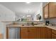 Open kitchen layout with stainless steel dishwasher, wooden cabinets, countertop, and breakfast bar overlooking living area at 3021 White Cloud Cir, Apex, NC 27502