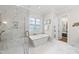 A luxurious bathroom featuring a soaking tub, separate shower with marble tile, and elegant fixtures at 329 Broad Elm Ln, Apex, NC 27523