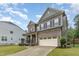 Beautifully designed home with a brick and siding exterior, a spacious driveway, and manicured landscaping at 352 Fire Opal Ln, Holly Springs, NC 27540