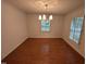 Empty dining room with hardwood floors, neutral walls, and a modern light fixture at 3911 Hope Valley Rd, Durham, NC 27707