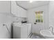 Well-lit laundry room with white washer and dryer, sink, and convenient access door at 3911 Hope Valley Rd, Durham, NC 27707