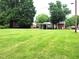 Expansive backyard with lush green lawn, a covered patio, and mature trees offers ample space and privacy at 404 Oakgrove Dr, Graham, NC 27253