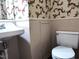 Small bathroom with a white sink, toilet, and vintage wallpaper at 404 Oakgrove Dr, Graham, NC 27253