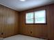 Bedroom with wood paneling, carpeting, and a window allowing natural light at 404 Oakgrove Dr, Graham, NC 27253