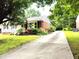Single-story home with brick accents, a well-manicured lawn, and a long driveway at 404 Oakgrove Dr, Graham, NC 27253