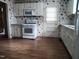 Vintage kitchen featuring white cabinets, laminate flooring, and floral wallpaper at 404 Oakgrove Dr, Graham, NC 27253