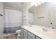 Bright bathroom featuring double sinks, neutral tile, and a shower-tub combination with curtain at 404 Straywhite Ave, Apex, NC 27539