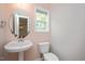 Charming powder room featuring a pedestal sink, a round mirror, and a toilet at 404 Straywhite Ave, Apex, NC 27539