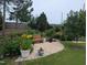 Lush backyard featuring a stone patio, a wooden bench, potted plants, and a variety of trees and greenery at 461 Cedar Pond Ct, Knightdale, NC 27545