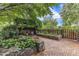 Inviting backyard patio area with brick pavers, stone planters, pergola, and mature trees and garden at 4620 Gomar Ln, Fuquay Varina, NC 27526