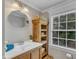 Well-lit bathroom with a window, vanity with sink, and a round mirror above the sink at 4620 Gomar Ln, Fuquay Varina, NC 27526