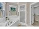 Bright bathroom with a soaking tub, large window, and glass-enclosed shower with access to a walk-in closet at 4620 Gomar Ln, Fuquay Varina, NC 27526