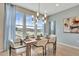 Dining area with a modern chandelier, large windows providing ample natural light, table set for a meal and wood floors at 5028 Jowetts Walk Dr # 24, Cary, NC 27519